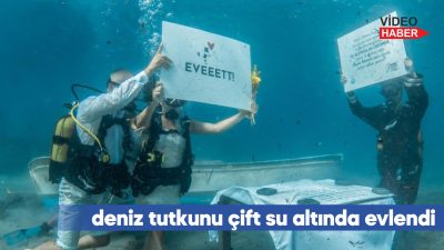 Çift, su altında "Evet" yazılı pankart açtıktan sonra kıyıya çıkarak