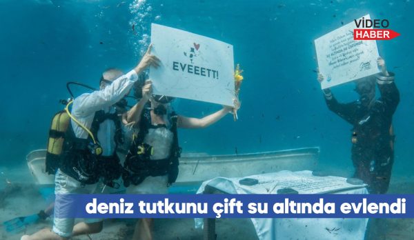 Çift, su altında "Evet" yazılı pankart açtıktan sonra kıyıya çıkarak